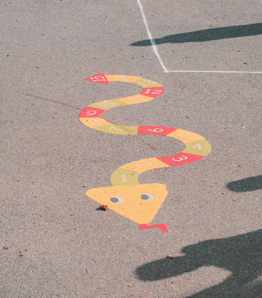 En bild av förskolans gård där en orm är målad på asfalten