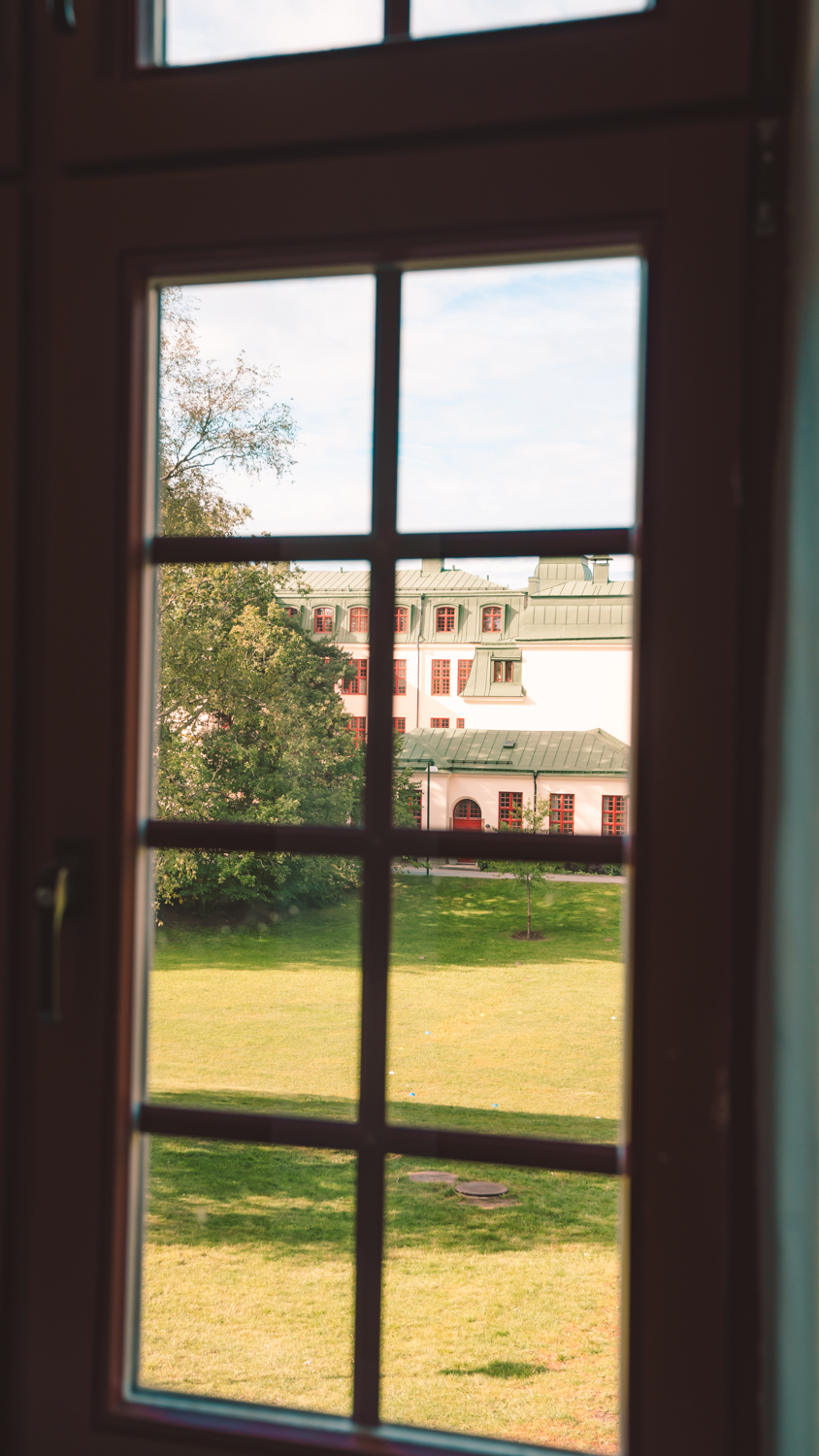 En bild genom skolans fönster med utsikt över skolgården